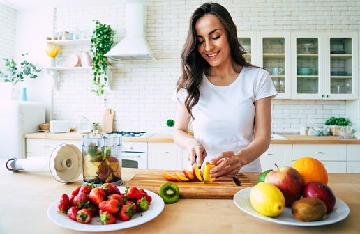  Mulher na cozinha cortando frutas para preparar o seu geladinho