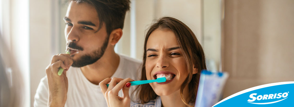 Home e mulher escovando os dentes