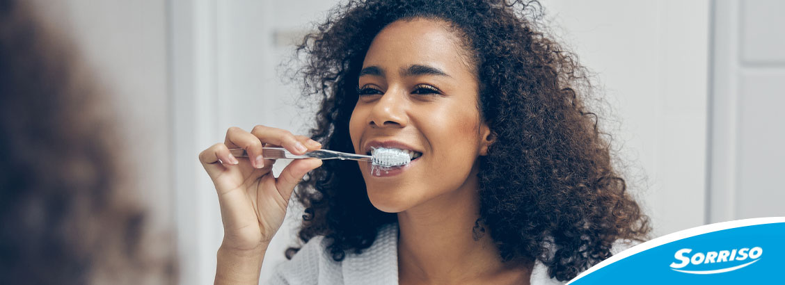 Mulher olhando no espelho para escovar os dentes Mulher olhando no espelho para escovar os dentes