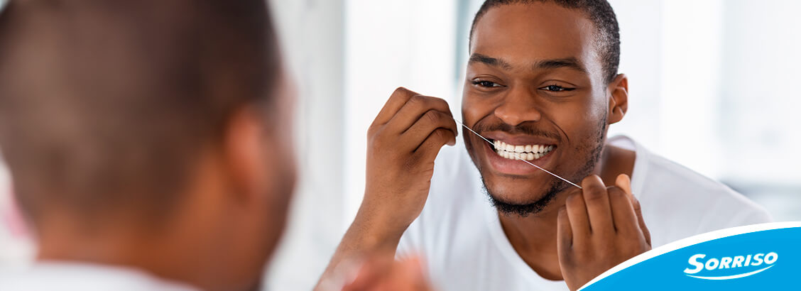Homem usando fio dental em frente ao espelho Homem usando fio dental em frente ao espelho