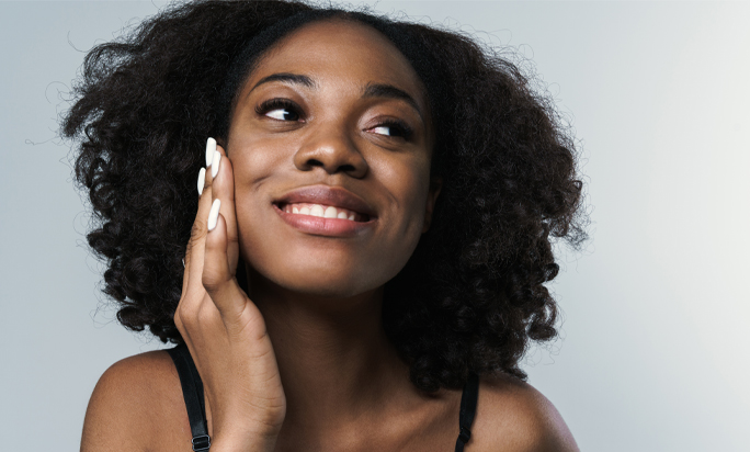 Mulher negra com a mão no rosto sorrindo com um sorriso naturalmente branco