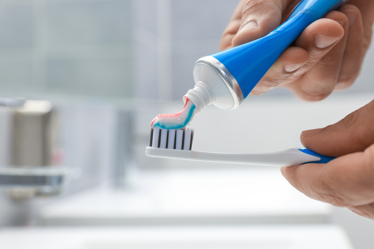 Pessoa coloca creme dental colorido em escova, ilustrando o uso da melhor pasta de dente para proteção eficaz e hálito fresco Pessoa coloca creme dental colorido em escova, ilustrando o uso da melhor pasta de dente para proteção eficaz e hálito fresco