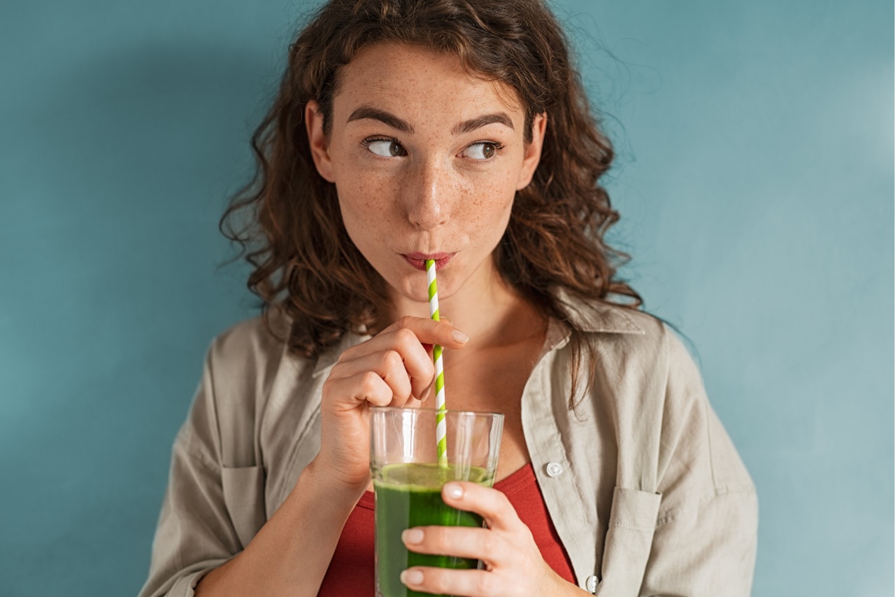 Mulher tomando uma bebida verde em um copo com canudinho, representando o tererê Mulher tomando uma bebida verde em um copo com canudinho, representando o tererê